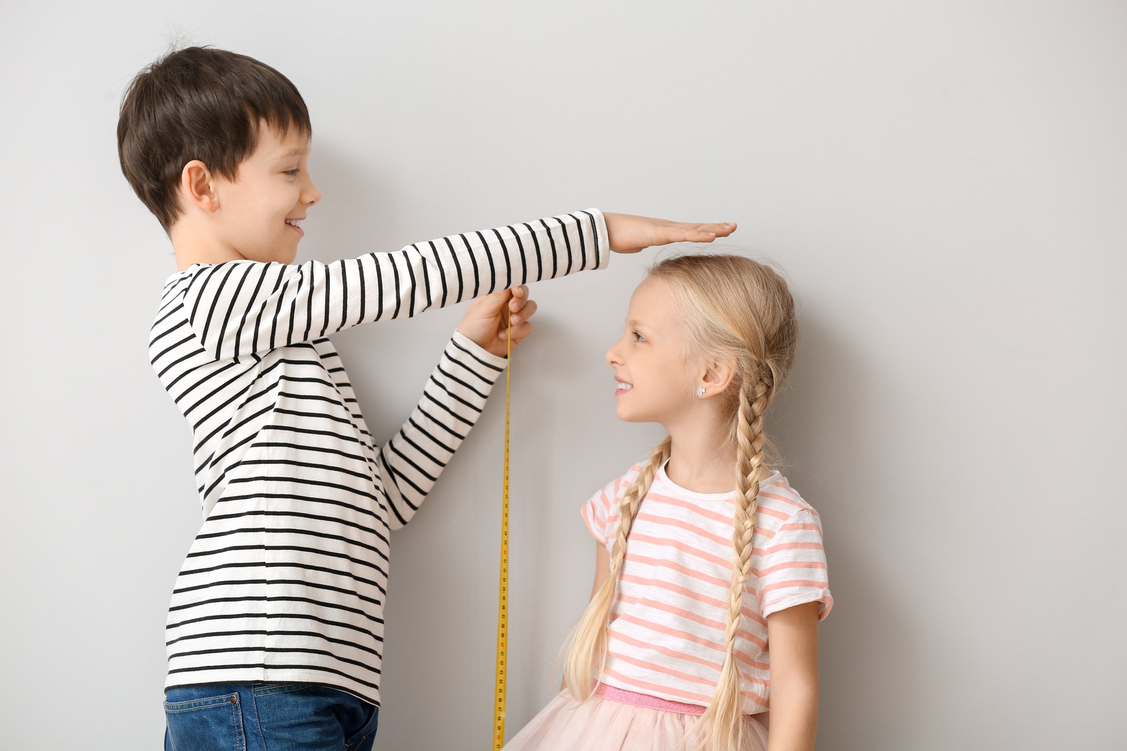 Cute Little Children Measuring Height near Wall